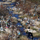 A woman crosses a stream running through land littered with plastic wastes in Shangxi village, eastern China’s Zhejiang province.